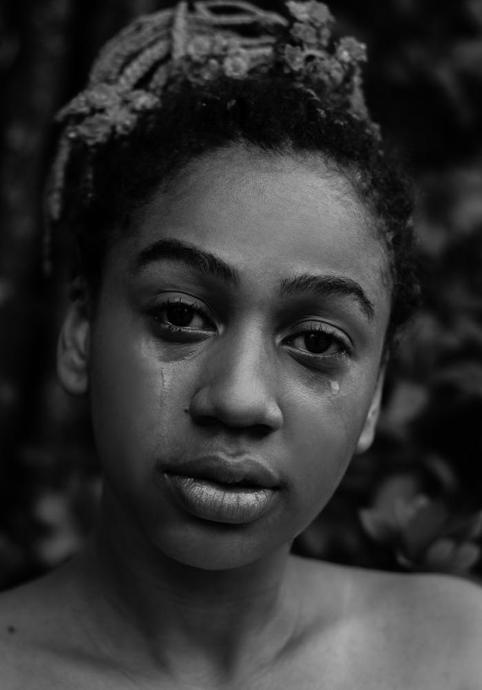 about-us A black and white portrait of a young woman expressing deep emotion with tears.